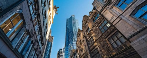 a striking juxtaposition of modern skyscrapers and traditional stone buildings in cardiff's vibrant cityscape, showcasing the architectural evolution through sharp angles and historic facades under a clear urban sky.